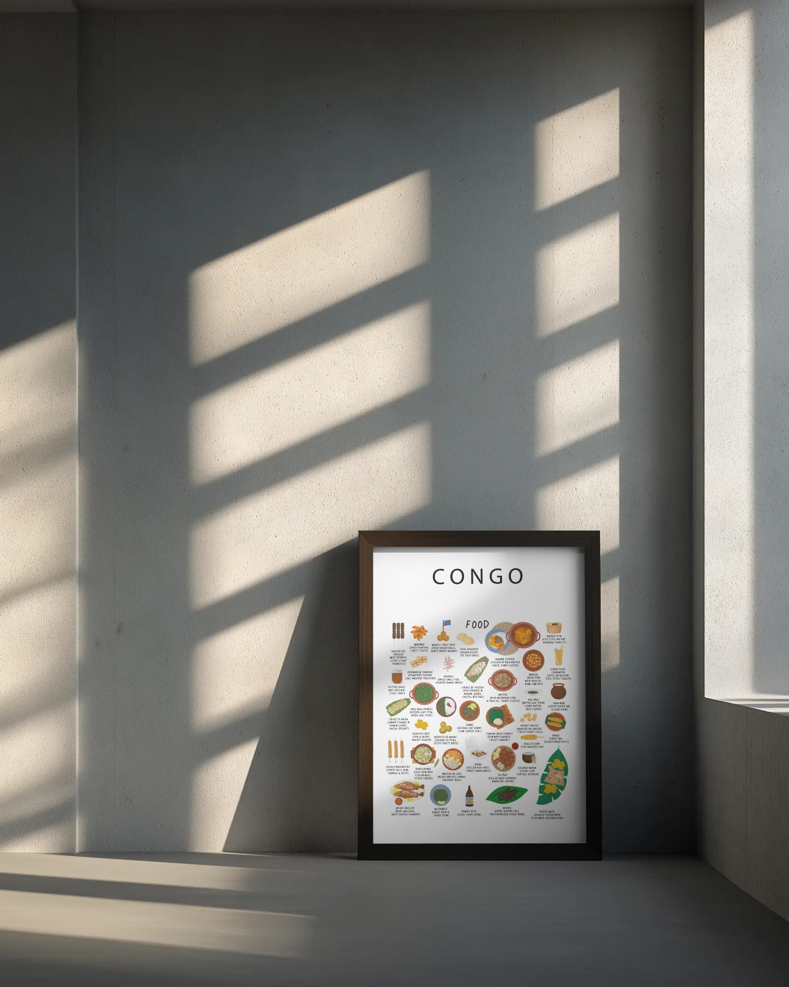 White framed Congo food poster leaning against a soft grey wall in warm afternoon light