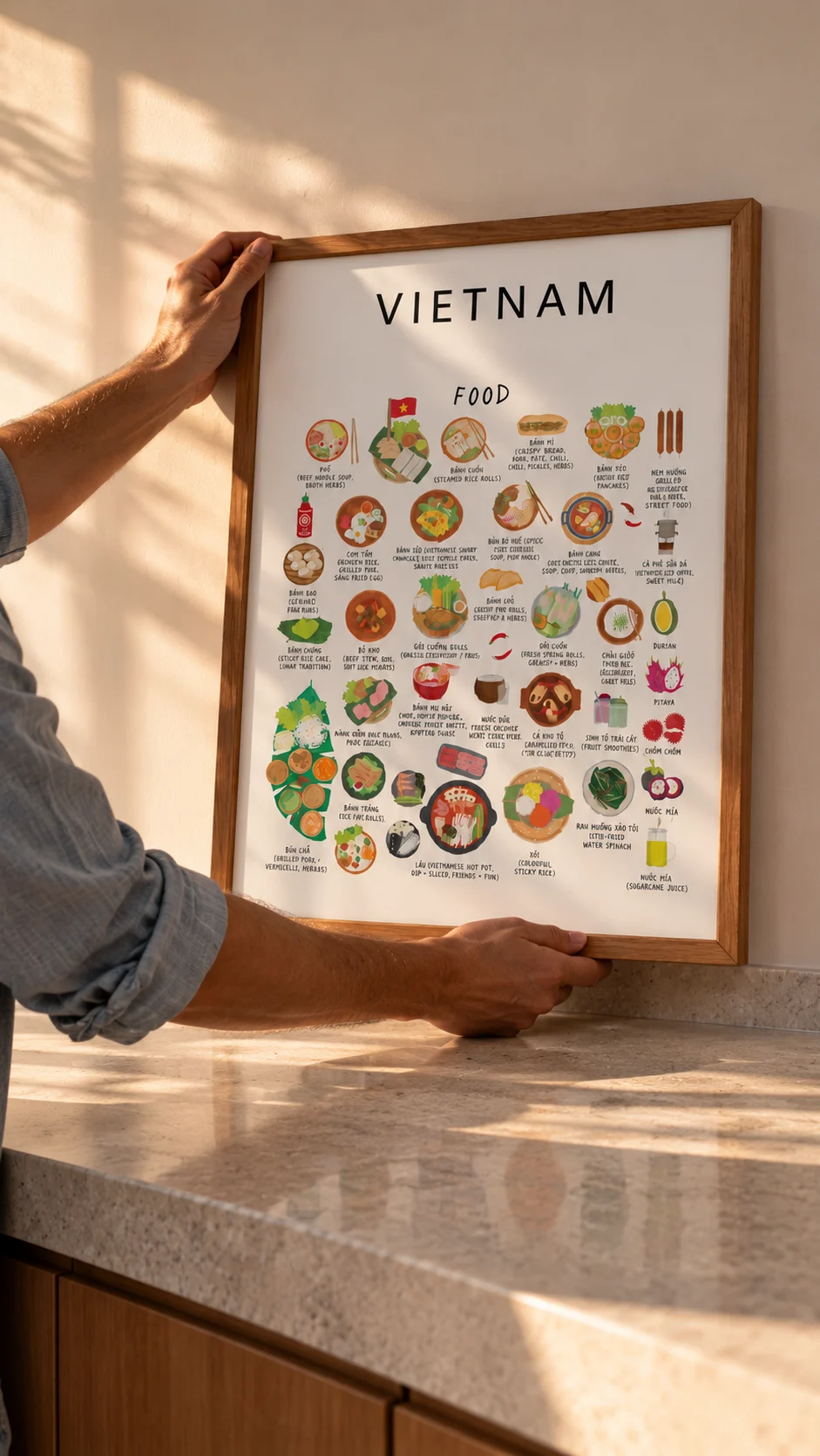 White framed Vietnam food poster held above a warm stone kitchen counter in afternoon light