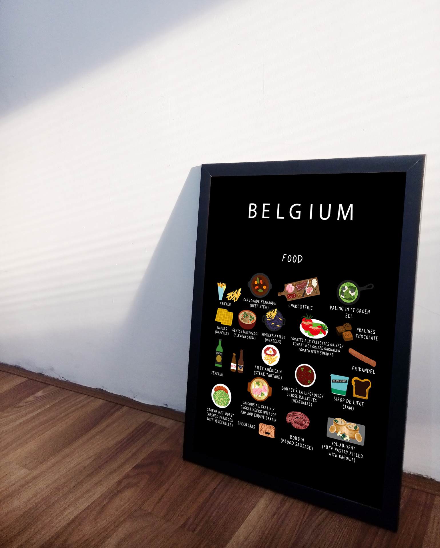 Black Belgium food poster in a black frame leaning against a soft white wall on wooden floor