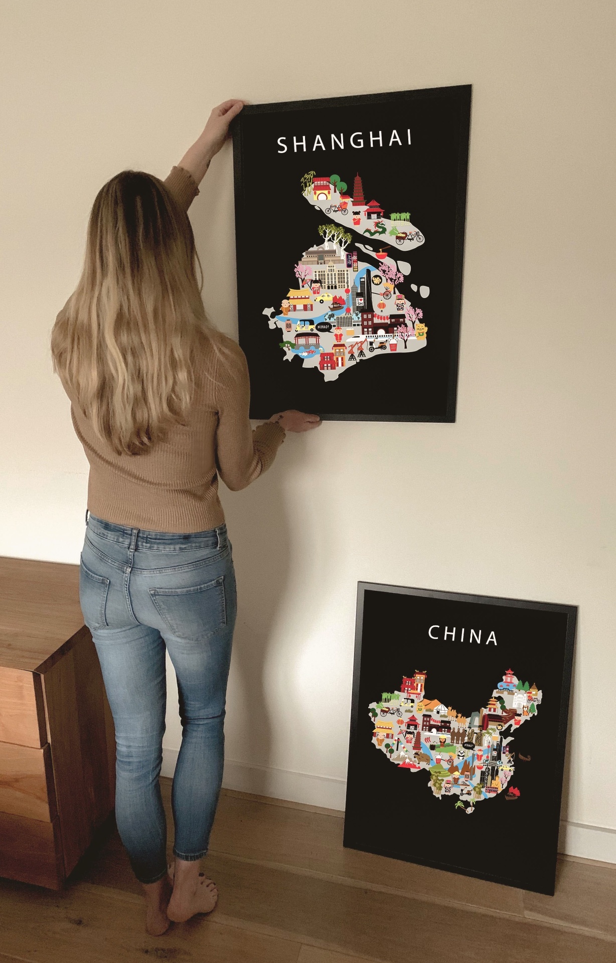 Anneke hanging the Maison Maps Shanghai and China illustrated posters on a soft white wall at home.