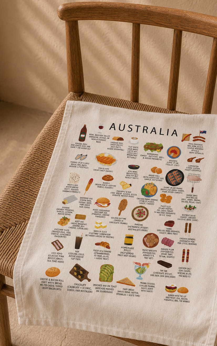 Maison Maps Australia illustrated tea towel draped over a woven wooden chair in warm daylight.