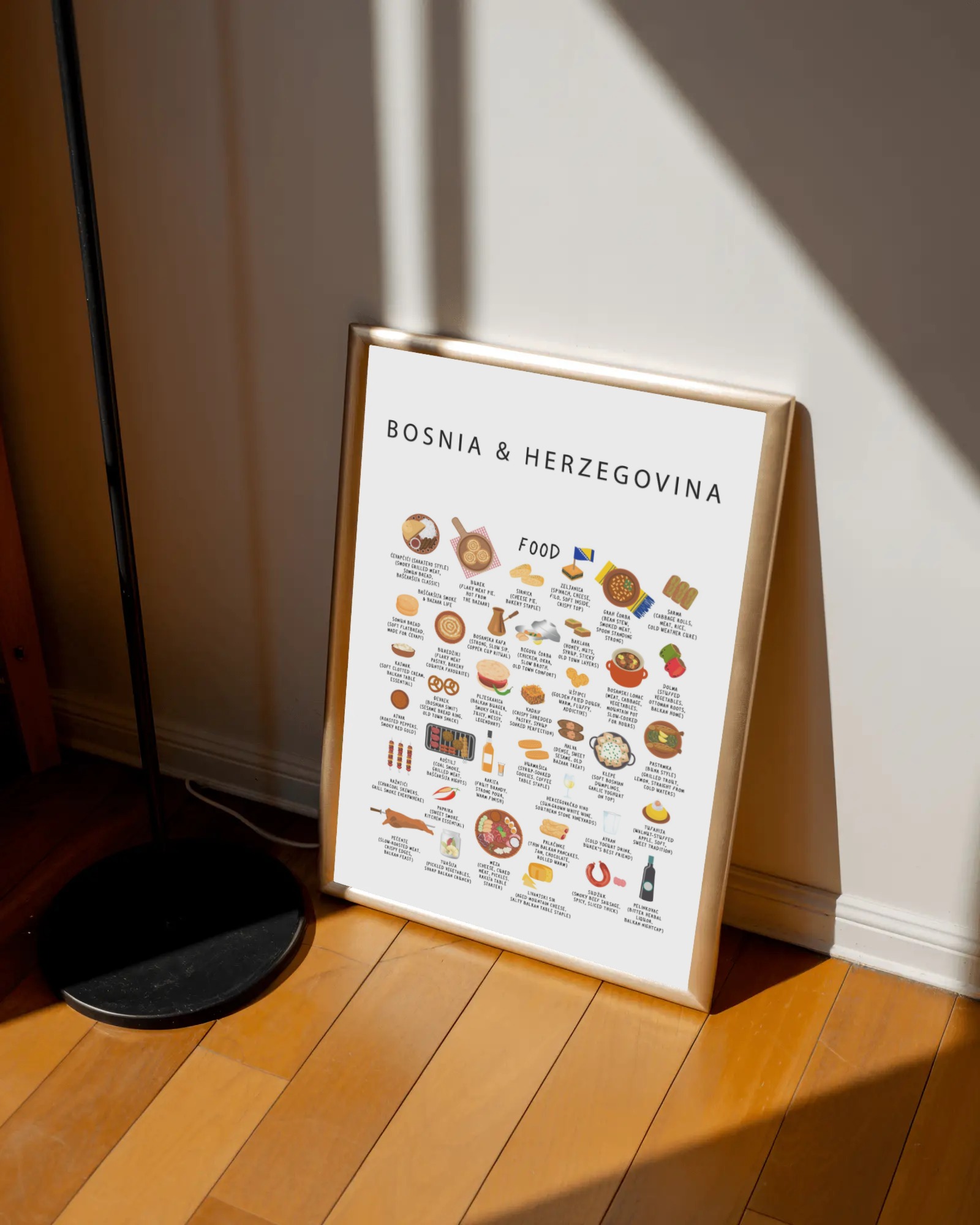 White Bosnia & Herzegovina food poster in a warm gold frame leaning against a soft wall on a wooden floor