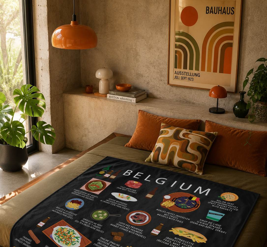 Black Belgium food blanket draped over a mossy green bed in a warm plaster-walled bedroom with orange velvet cushions