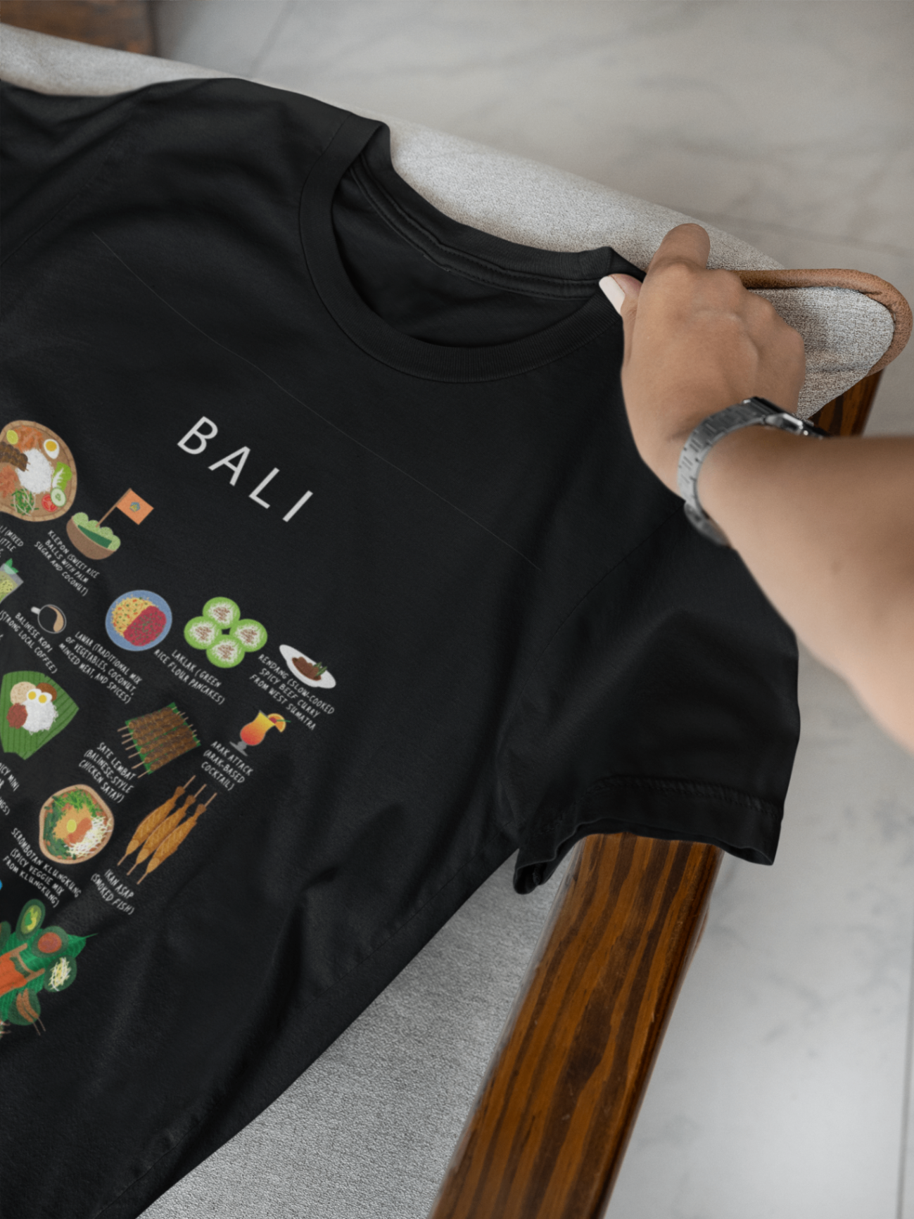 Black Bali food t-shirt folded on a linen bench in soft natural light