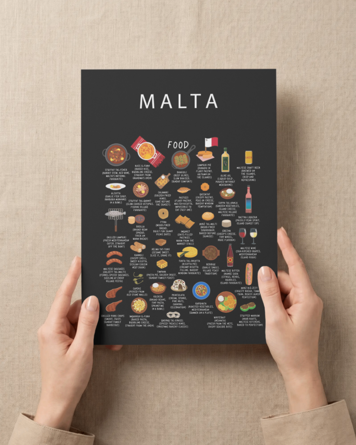 Black Malta food poster held gently against a warm linen backdrop