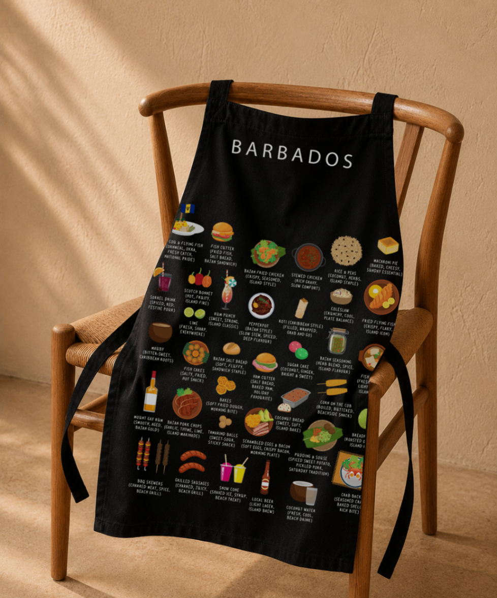 Black Barbados food apron hung on a wishbone wooden chair in warm afternoon light