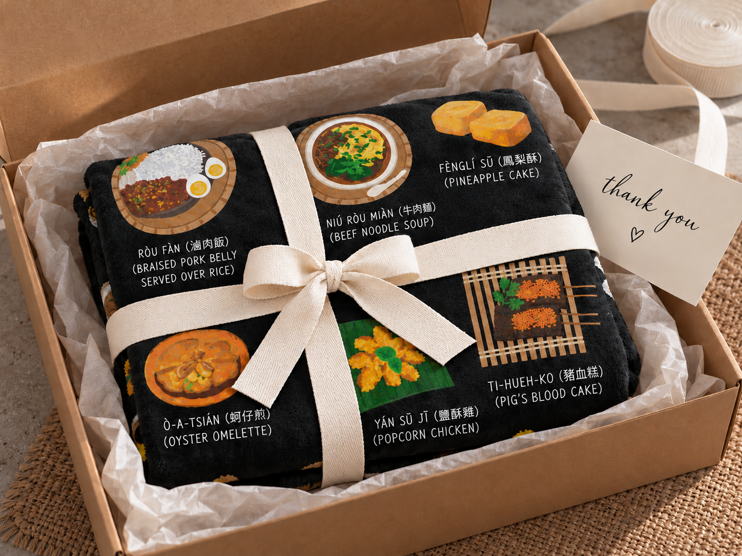 Taiwan food blanket folded with a cream ribbon inside an open gift box with a thank you card