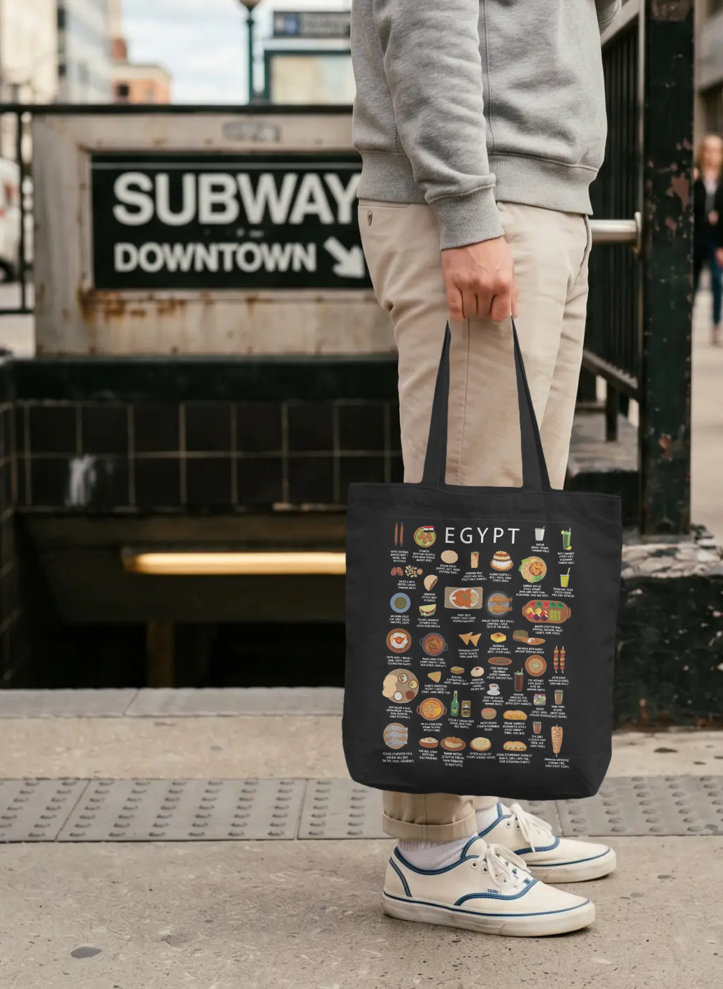 Black Egypt food tote bag held on a downtown subway street in soft overcast daylight