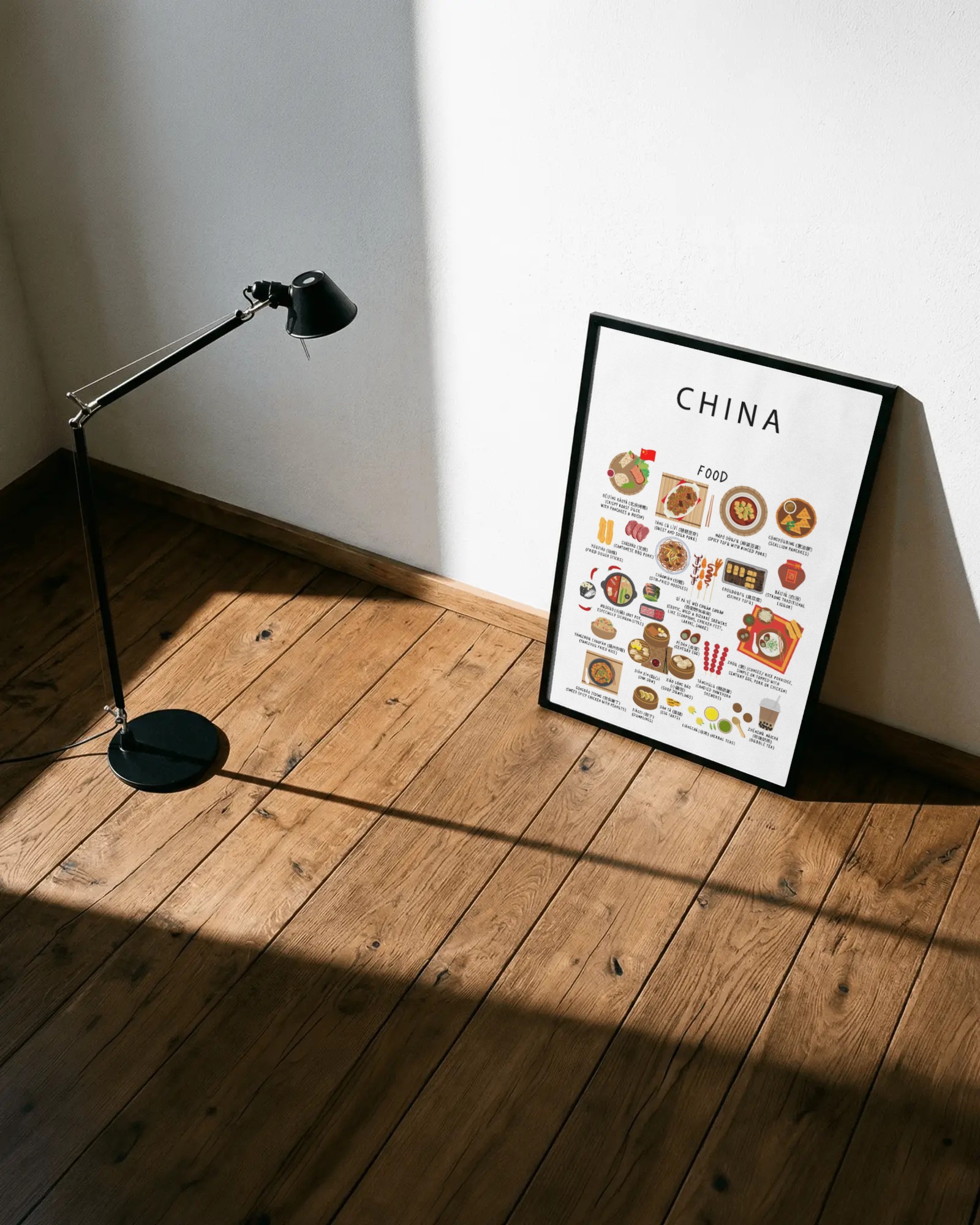White China food poster framed and leaning on a sunlit wooden floor beside a black studio lamp