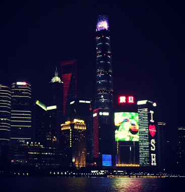 The illuminated Shanghai Pudong skyline at night, with the Shanghai Tower and neighbouring skyscrapers glowing above the Huangpu river.