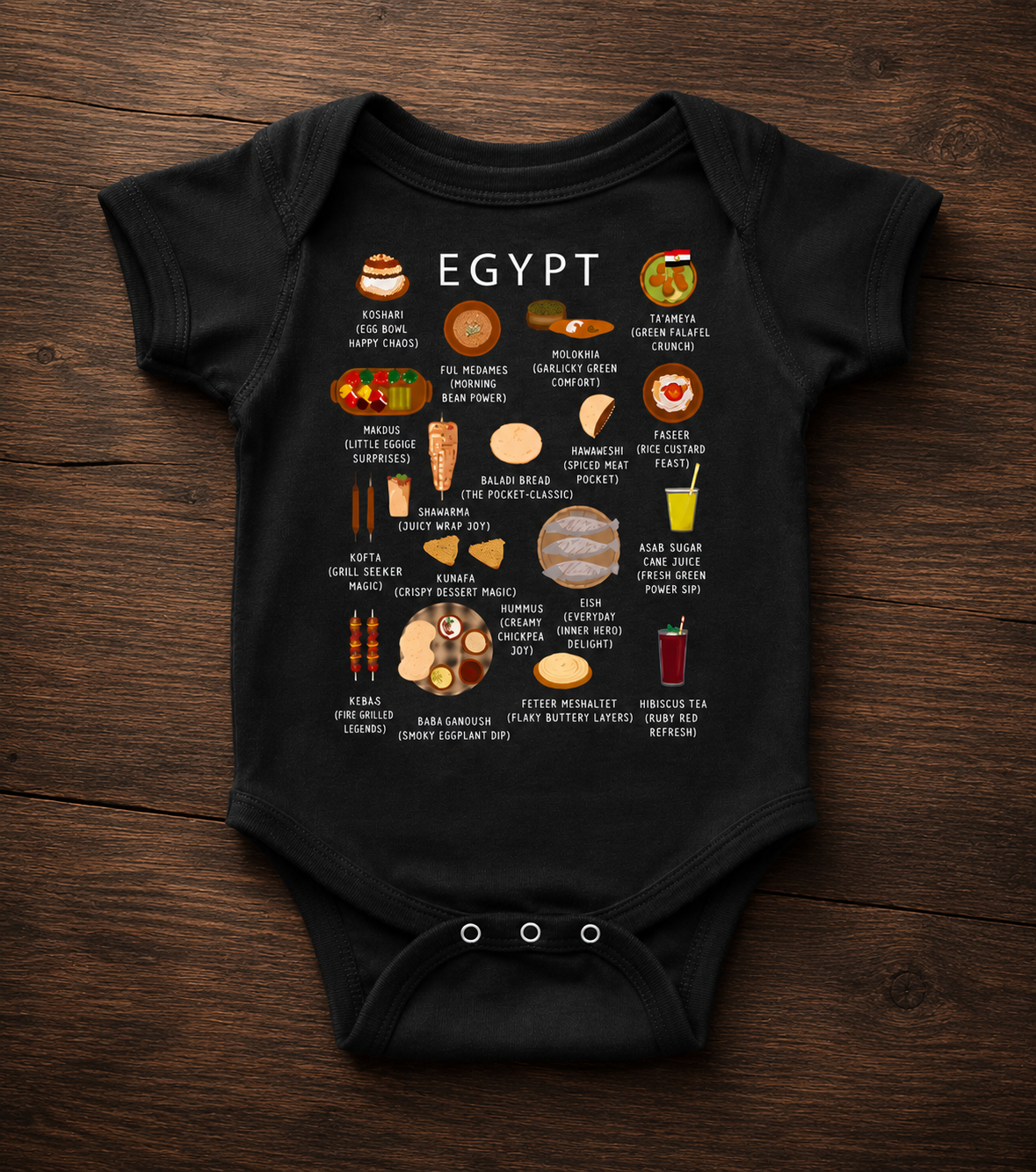 Black Egypt food baby onesie laid on a dark wooden surface with warm overhead light