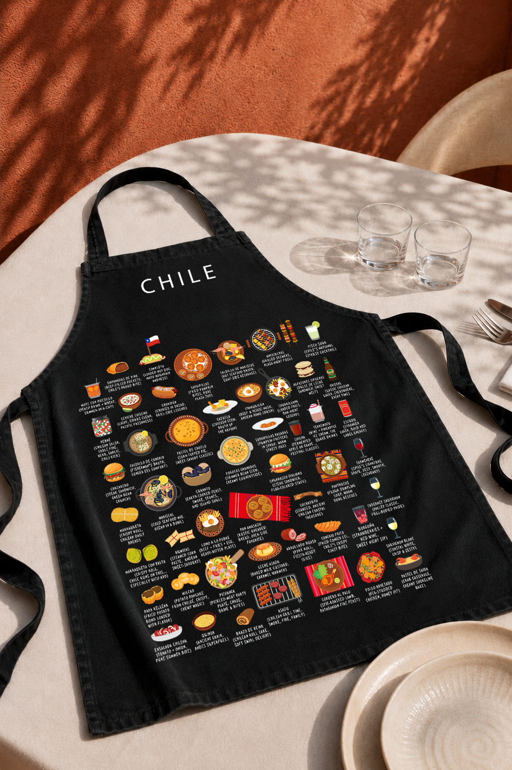 Black Chile food apron on a sunlit linen table with glassware and soft dappled shadow