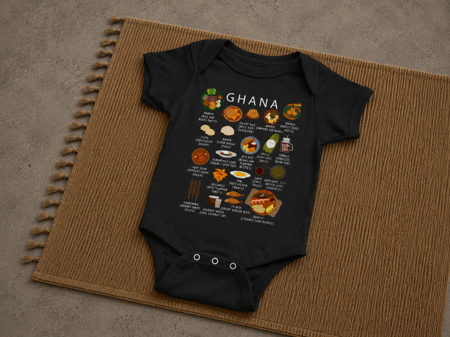 Black Ghana food baby onesie styled on a woven jute mat